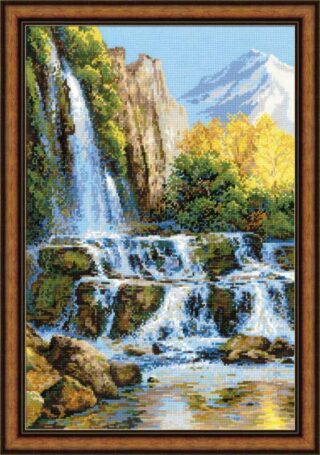 Landscape cross stitch of a cascading waterfall with rocks, green trees, golden autumn foliage, and distant snow-capped mountains under a clear blue sky.