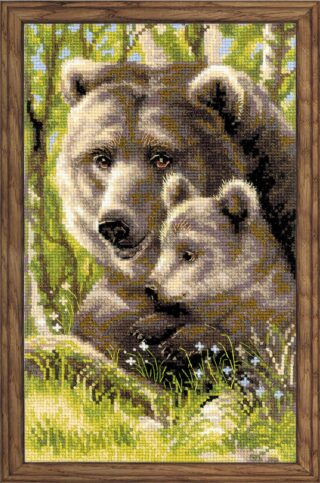 Close-up cross-stitch artwork of a brown bear and its cub resting together in a green forest, framed in rustic wood.