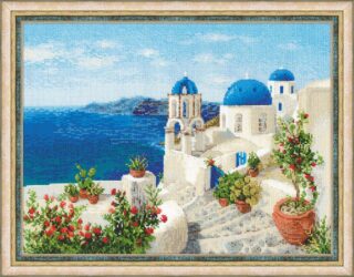 Cross stitch design of a sunny coastal scene in Santorini with white buildings, blue domes, and flowering plants by the sea.
