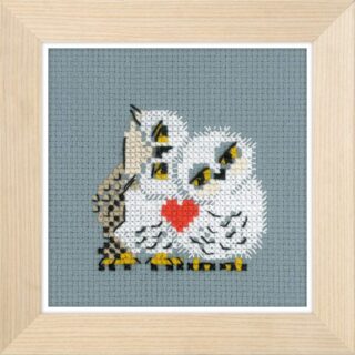 Cross-stitched family of three owls cuddling together with a red heart on their chests, stitched on gray fabric.