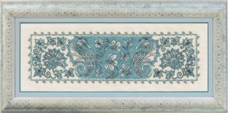 A blue and white cross-stitch design of two stylized seahorses surrounded by floral and shell patterns.