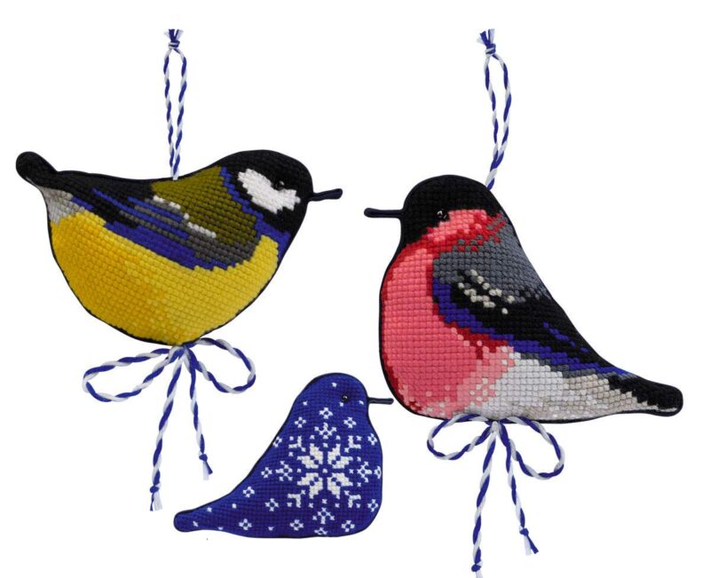 Three colorful cross-stitched bird ornaments in winter hues, featuring a great tit, bullfinch, and snowflake design on blue fabric.