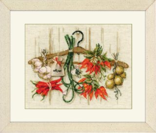 A cross-stitched bundle of garlic, onions, chili peppers, and herbs hanging from a wooden hanger.