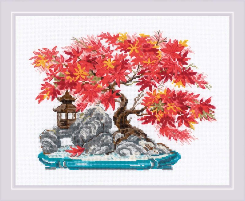 A vibrant cross stitch design of a bonsai tree with bright red and orange autumn leaves, set on a rocky base with a small lantern decoration.