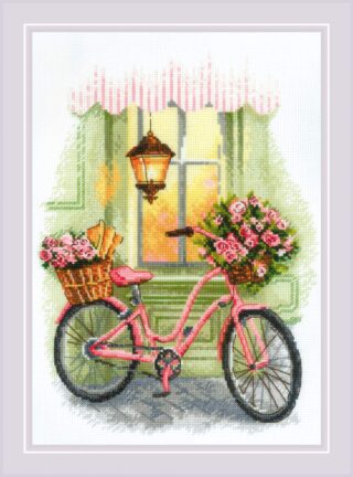 A pink bicycle with baskets of pink roses and fresh baguettes, parked by a green storefront under a warm glowing lantern.