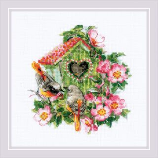 Two birds perched near a green birdhouse with a heart-shaped entrance, surrounded by pink blooming flowers.