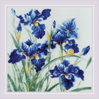 Cross-stitch embroidery of vibrant blue irises with yellow and white accents, surrounded by long green leaves. A small yellow snail sits on one of the curved leaves, adding a charming detail. The flowers are set against a light background and framed with a soft lavender border. Design from RIOLIS kit 2102.