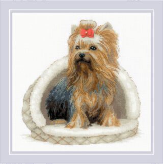 Cross-stitch design of a Yorkshire Terrier with a red bow, sitting in a cozy white pet bed.