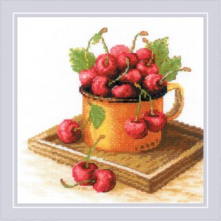 Cross-stitch design of a rustic yellow mug filled with ripe red cherries, some spilling onto a wooden board.