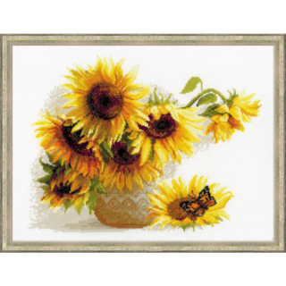 A cross-stitch artwork of bright sunflowers in a vase, with a butterfly resting on a fallen bloom, stitched on white fabric.