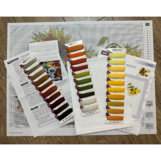 A cross-stitch artwork of bright sunflowers in a vase, with a butterfly resting on a fallen bloom, stitched on white fabric.