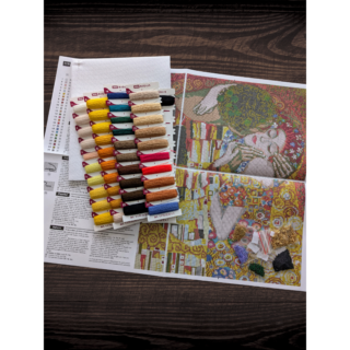 Cross stitch of Gustav Klimt’s "The Kiss" featuring a couple in an embrace, surrounded by golden geometric and floral patterns.