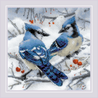 A winter-themed cross-stitch of two blue jays perched on snowy branches with red berries and soft gray shadows in the background.