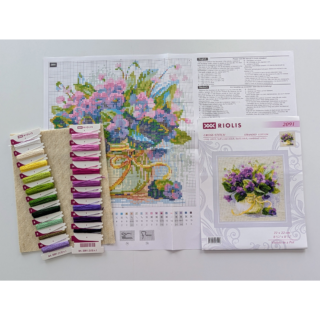 A white pot filled with vibrant purple violets and lush green leaves, tied with a soft yellow ribbon.