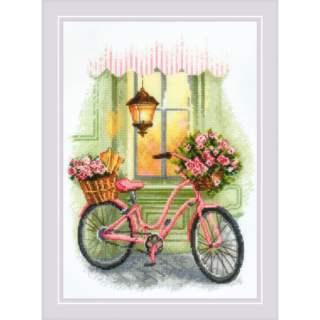 A pink bicycle with baskets of pink roses and fresh baguettes, parked by a green storefront under a warm glowing lantern.