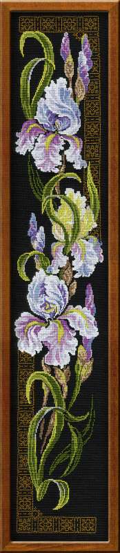 Vertical cross-stitch embroidery of tall irises in soft shades of white, lavender, and pale yellow, accented with green leaves. The flowers are set against a striking black background with gold geometric border details. Framed in a narrow wooden frame. Design from RIOLIS kit 841.