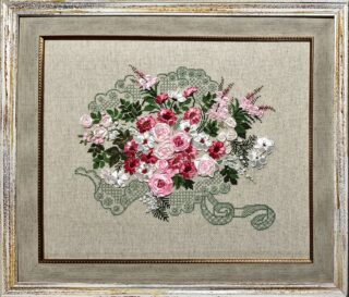 Framed embroidery of a lace-patterned basket filled with pink and white roses and green leaves.