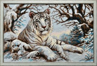Framed embroidery of a white tiger lying in the snow under bare trees in a winter forest scene.
