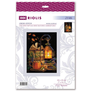 Cross-stitch design of a glowing lantern on a wooden table with books, a pumpkin mug, autumn leaves, and cozy fall accents.