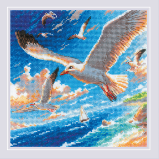 Cross-stitch design featuring seagulls soaring above a sparkling blue sea with a sailboat in the distance and waves crashing against a rocky shore.