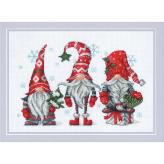 Three festive Christmas gnomes in red hats holding holiday decorations with snowflakes falling around them.