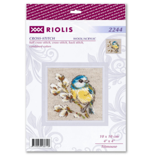 Cross-stitch design of a blue and yellow titmouse perched on a blooming branch with white flowers, stitched on natural-colored fabric.