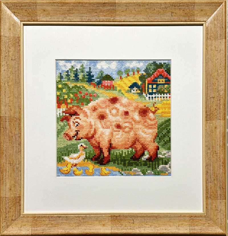 Framed embroidery of a pink pig beside a pond with ducks and ducklings in a colorful farmyard scene.