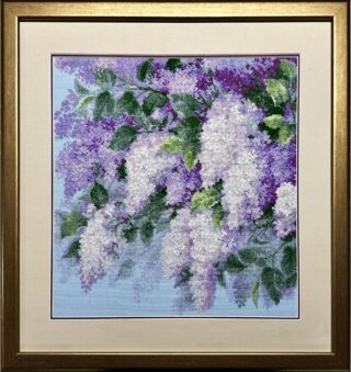 Framed embroidery of lilac flowers in shades of purple and white with green leaves on a blue background.