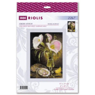 Elegant still life cross-stitch featuring soft pink and white calla lilies in a glass vase with an oyster shell and lemon slice.