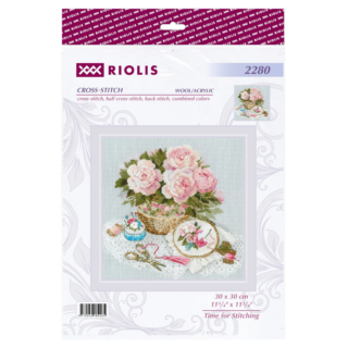 Cross-stitch kit showing a basket of pink roses beside embroidery tools, lace fabric, and a hoop with a stitched floral design.