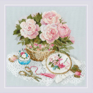 Cross-stitch kit showing a basket of pink roses beside embroidery tools, lace fabric, and a hoop with a stitched floral design.