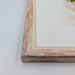 Framed cross-stitch artwork showing a pastel pink wedding bouquet with green foliage and a soft ribbon on a light background.