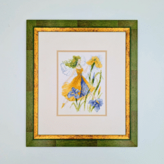 Framed cross-stitch artwork of a fairy in a yellow dress surrounded by blue and yellow flowers on a light background.