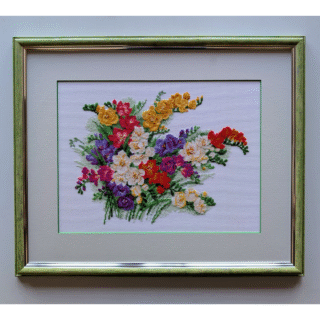 Framed cross-stitch artwork featuring a colorful bouquet of freesia flowers in yellow, red, purple, and white on a light background.