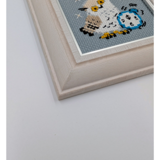Stitched and framed embroidery artwork showing a small owl beside an alarm clock on a soft gray background.