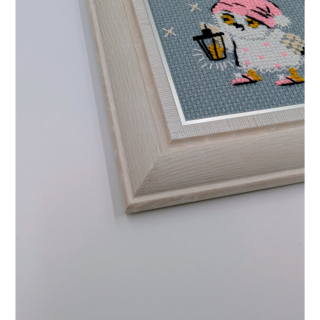 Stitched and framed embroidery artwork showing a small owl in a pink night cap holding a lantern on a soft gray background.