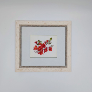 Stitched and framed embroidery artwork featuring a delicate branch of red blossoms with green leaves on a light background.