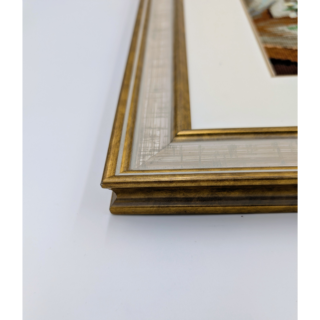 Stitched and framed embroidery artwork showing a vase of white snowdrops on a table beside a sunlit window.