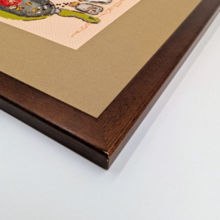 Stitched and framed embroidery artwork depicting a playful breakfast scene with a fried egg, tomatoes, bread, coffee items, and a skillet arranged in mid-air.