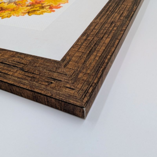 Stitched and framed embroidery artwork showing two children playing with a dog in a pile of golden autumn leaves.