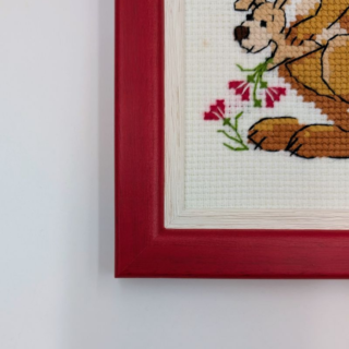 Stitched and framed embroidery artwork depicting a kangaroo family with joeys and flowers on a light background.