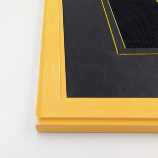 Stitched and framed embroidery artwork depicting a colorful dreamcatcher with feathers, beads, and geometric patterns on a black background.