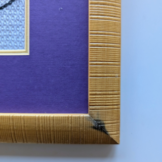 Framed stitched artwork featuring stylized butterflies in shades of blue, violet, and soft peach on a textured light background.