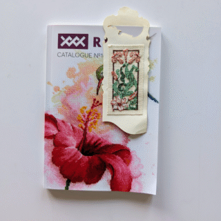 Hand-stitched floral bookmark featuring pink flowers and green leaves in an elegant decorative frame.