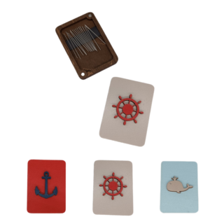 Rectangular wooden needle cases with magnetic interiors featuring nautical motifs: a red ship wheel, blue anchor, and smiling beige whale on pastel backgrounds.
